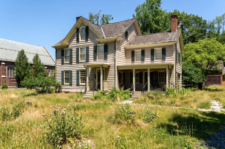 Vintage Victorian house with lush yard and mature trees.
