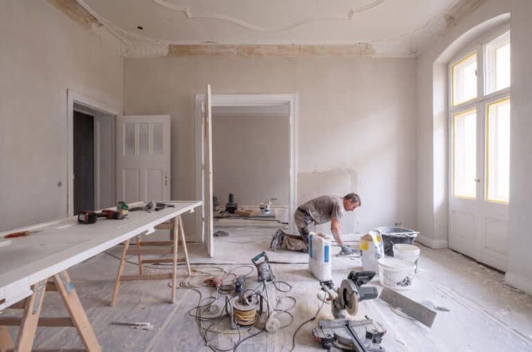 Interior renovation of a commercial property with a worker installing flooring.