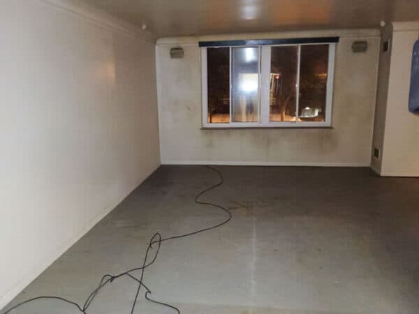 Empty room with large window and concrete floor at night.