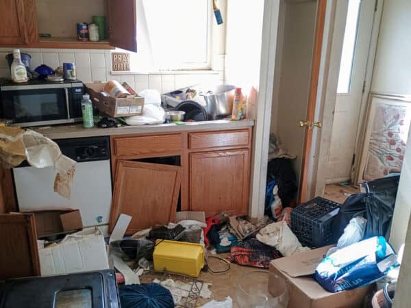 Cluttered kitchen with trash and disorganized items in a residential property.