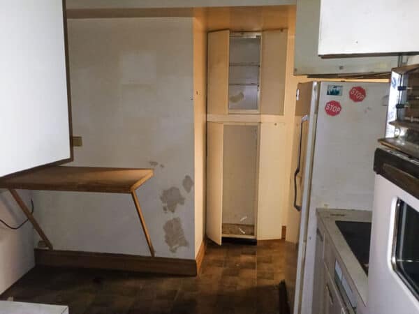 Kitchen space with wooden cabinets and appliances in renovation.