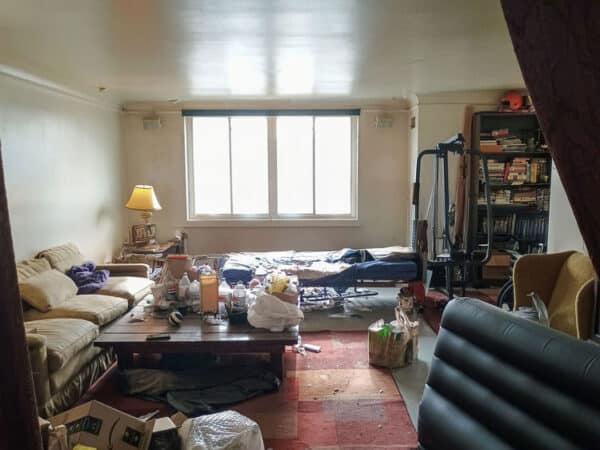 Living room with clutter and disorganized furniture in a residential property.