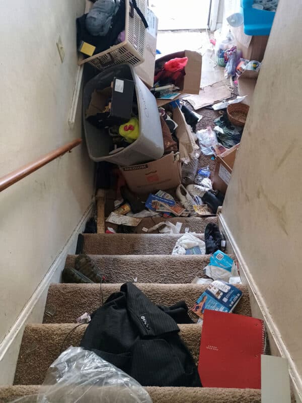 Messy staircase with clutter, boxes, and personal items in a residential home.
