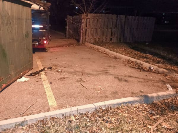 Empty parking lot at night with debris and fallen leaves.
