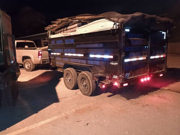 Equipment trailer loaded with construction materials at night.
