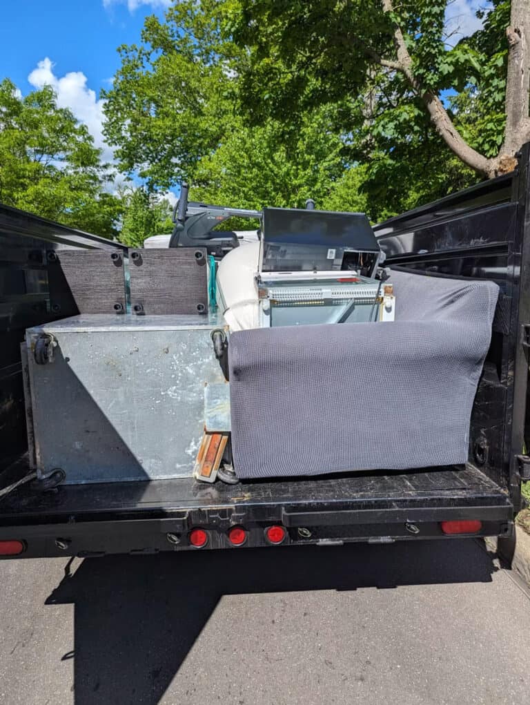 Junk removal truck loaded with furniture and appliances for disposal.